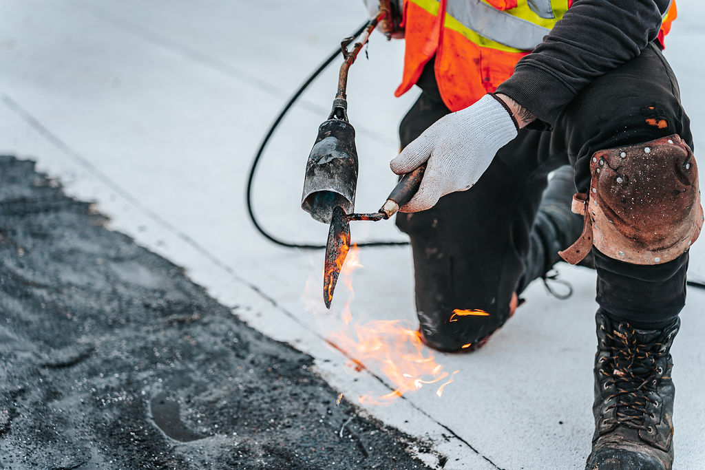 Homme travaillant sur une toiture avec une torche