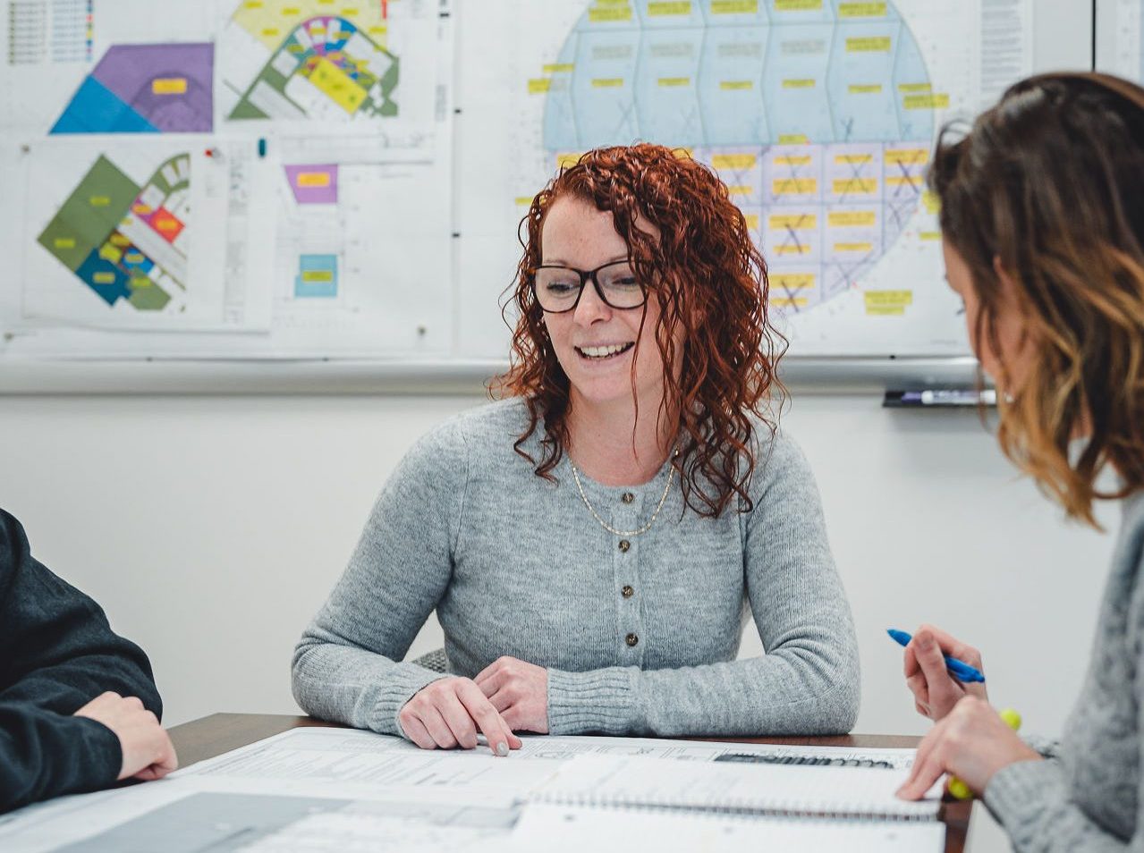 femme rousse expliquant des plans au bureau