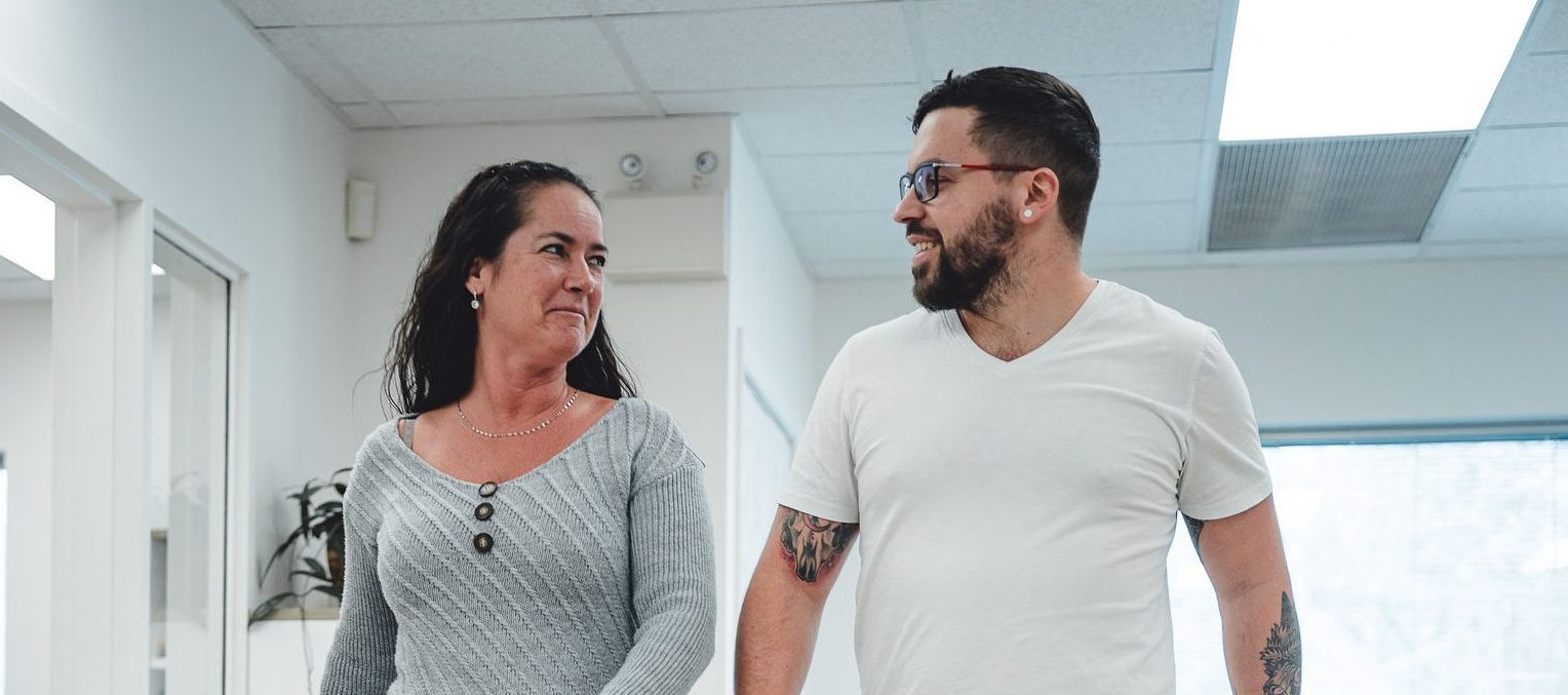 femme et homme souriant en marchant au bureau